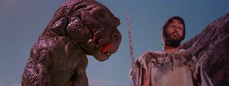 A dinosaur liking his lips looking at a caveman played by Ringo Starr