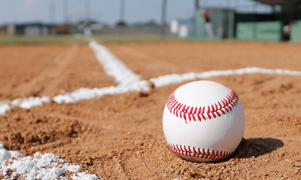 a single baseball sitting in the dirt