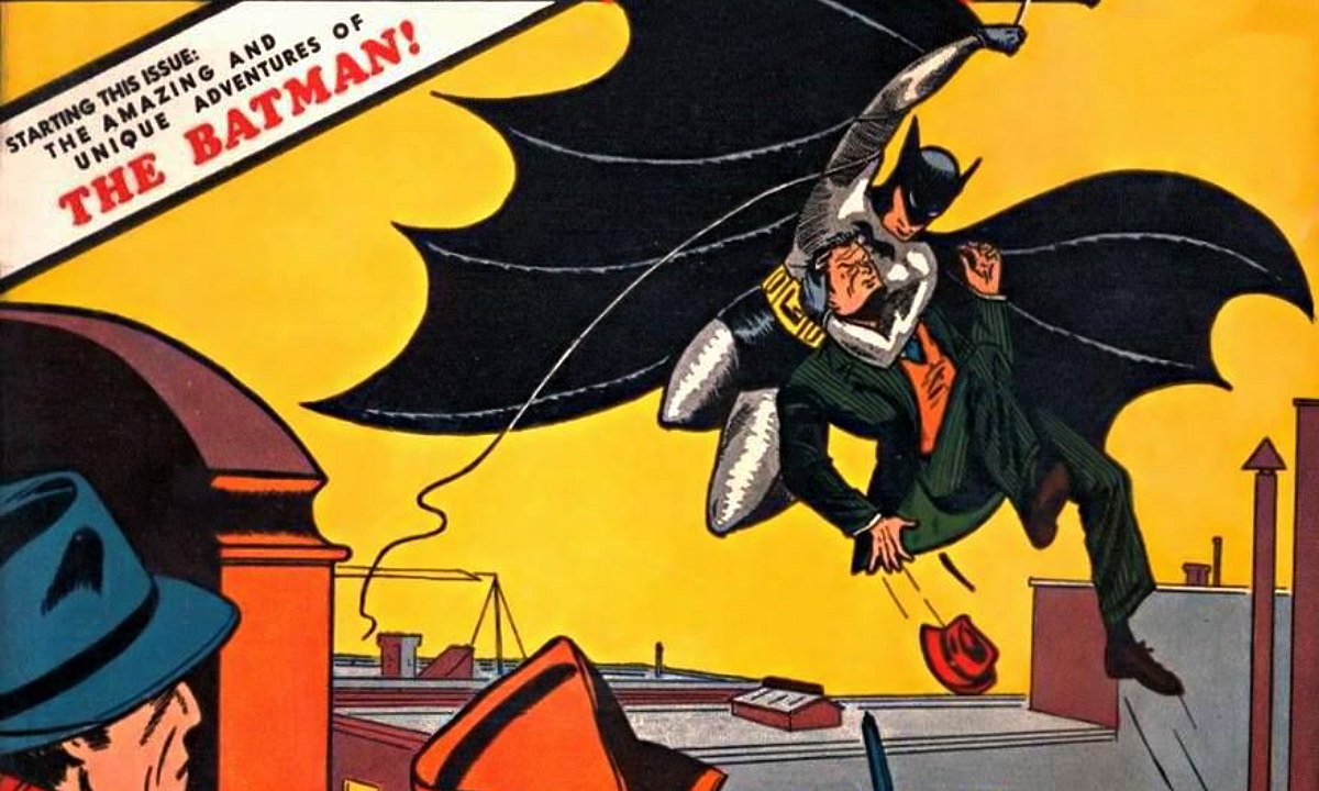 Batman swings in and grabs a bad guy