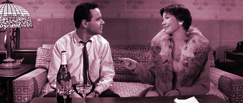 Jack Lemmon and Shirley MacLaine sit on a couch talking in the movie "The Apartment".