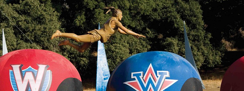 A woman leaps over two "big balls" from the "Wipeout" TV show.