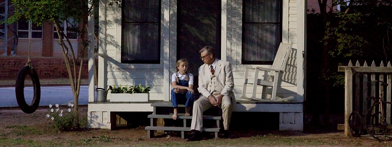 A man and a girl sitting on a front porch.