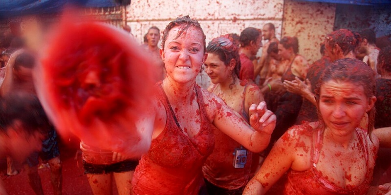 A young woman throws a rotten tomato at the camera during La_Tomatina in Spain