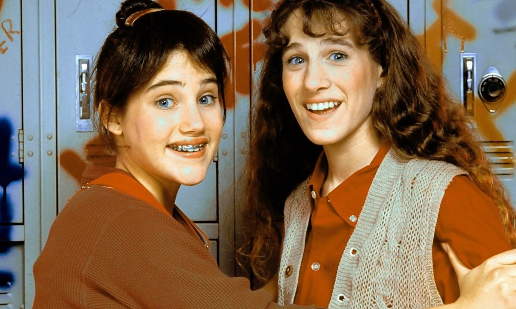 Two high school students standing in front of some school lockers.