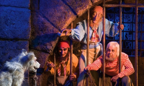 Three prisoners try to coax a dog with a key inside Disneyland's Pirates of the Caribbean ride