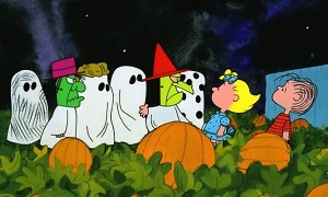 A group a kids in costume talking to Sally and Linus in a pumpkin patch