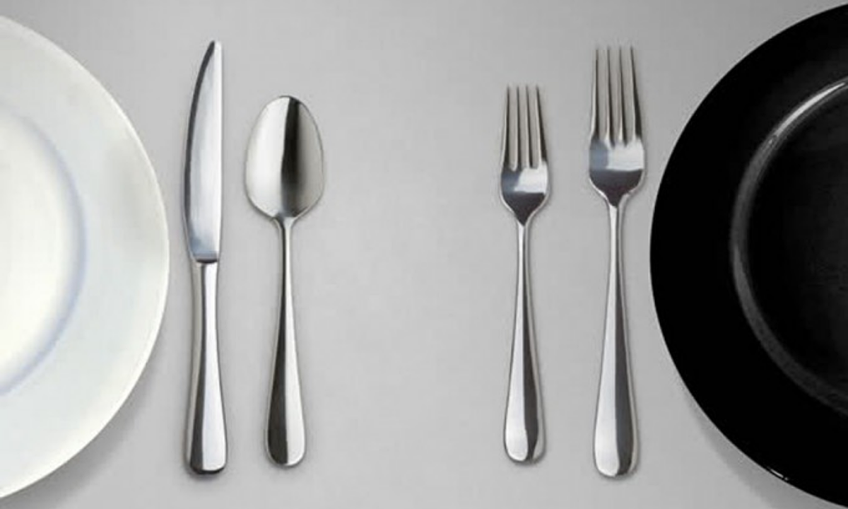 one white plate sits next to a black plate and silverware