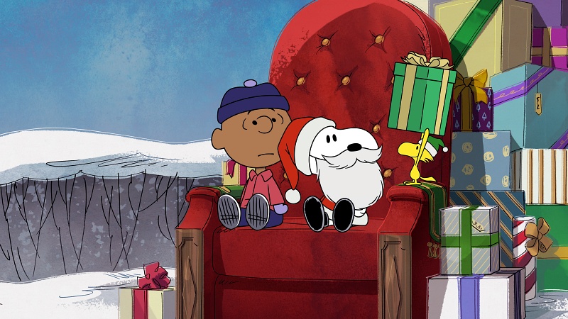 Snoopy dressed like Santa Claus, a little boy and woodstock holding a big present.