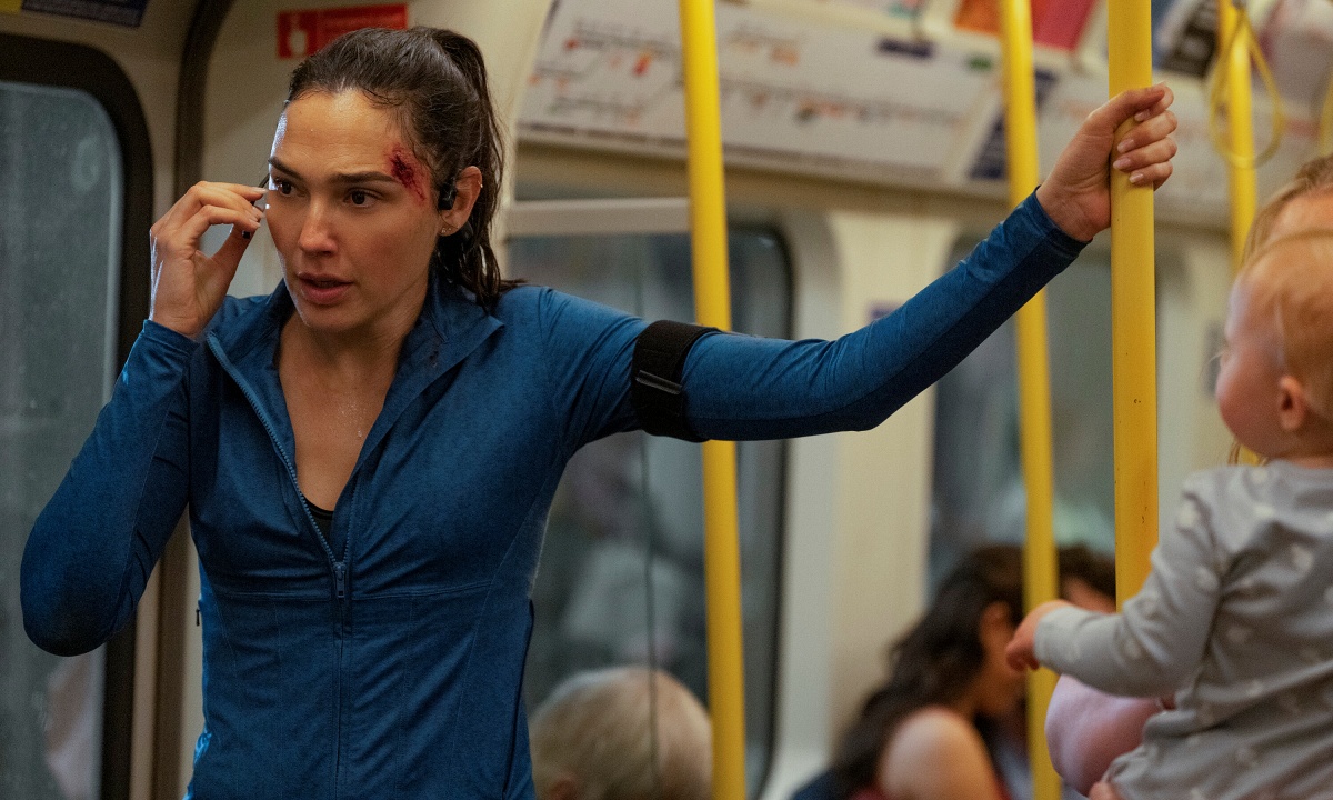 Gal Gadot talking on the phone on a subway train.